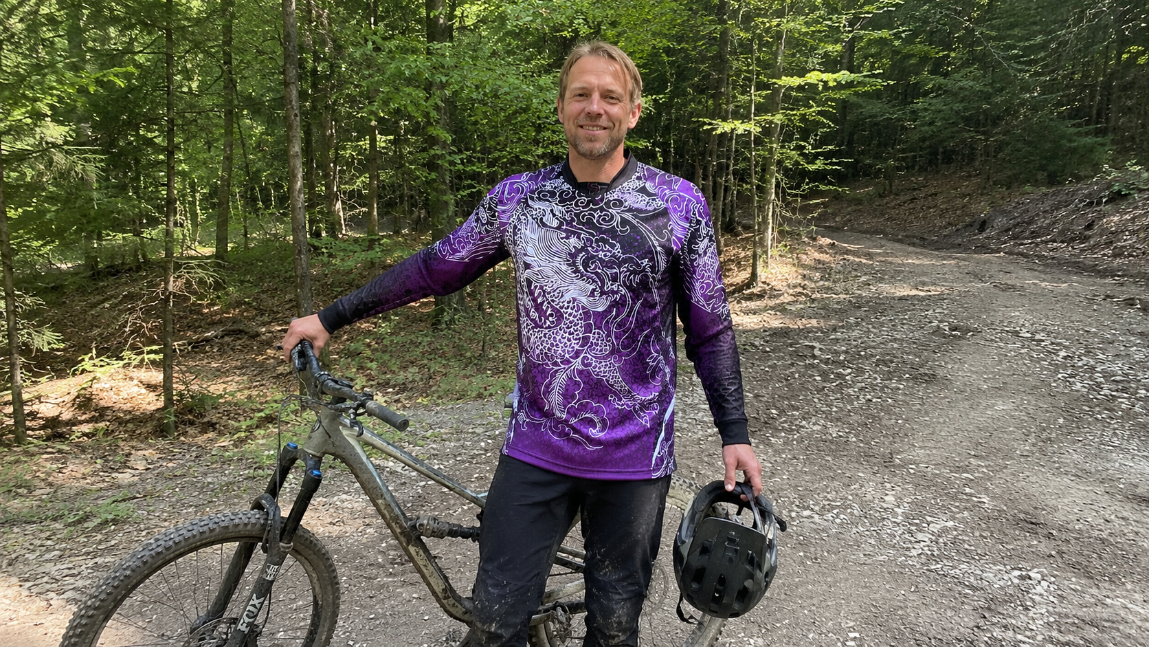 Violettes MTB Jersey mit individuellem Design Mountainbiker Dave im violetten MTB Jersey neben seinem Bike im Wald