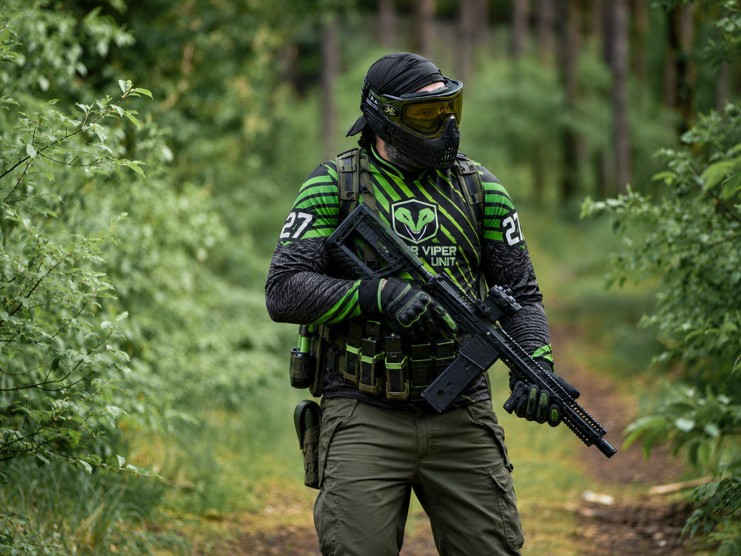 Paintballspieler im grünen Jersey auf einem Woodland-Spielfeld